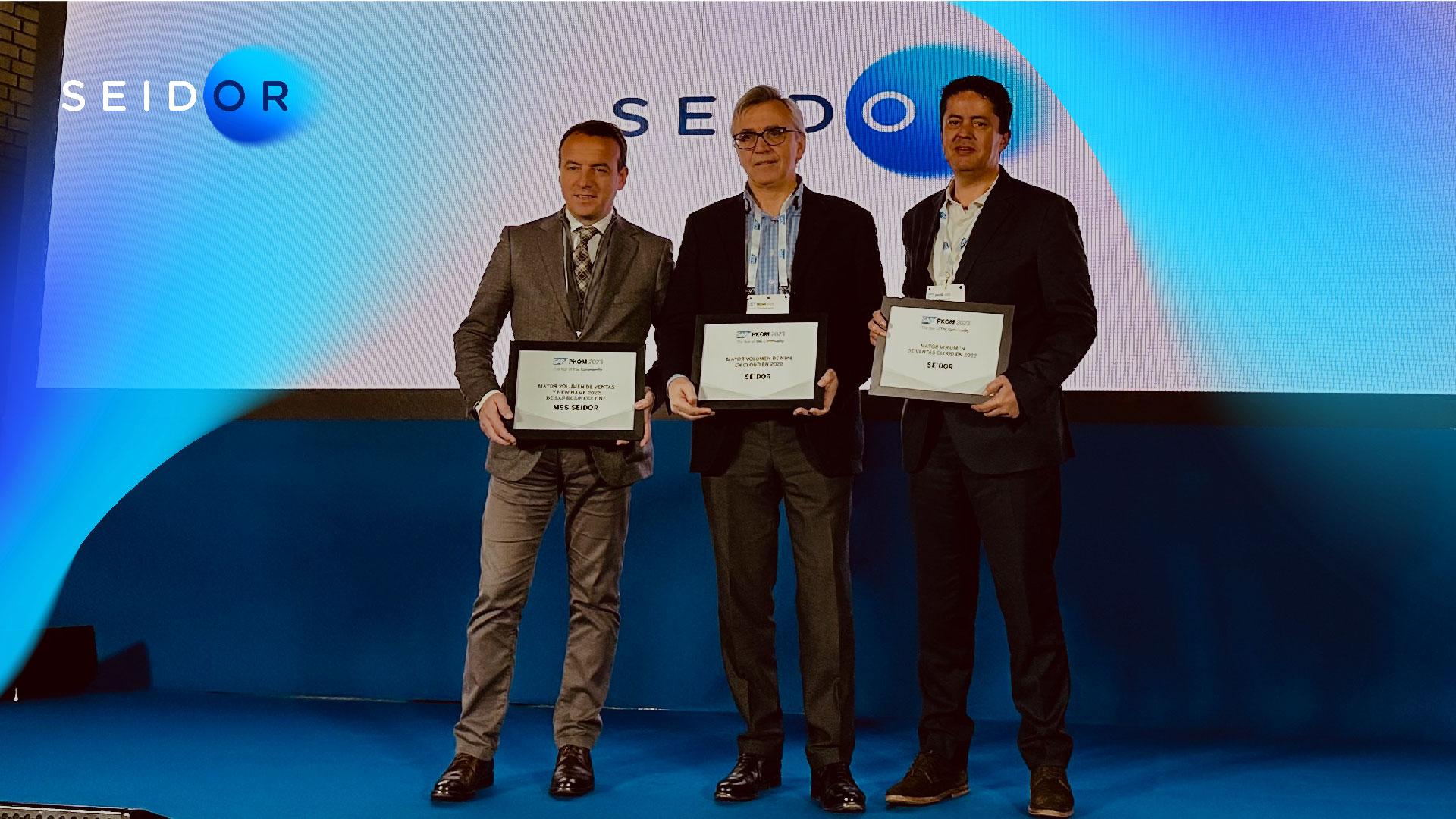 tres personas en un escenario mostrando un premio