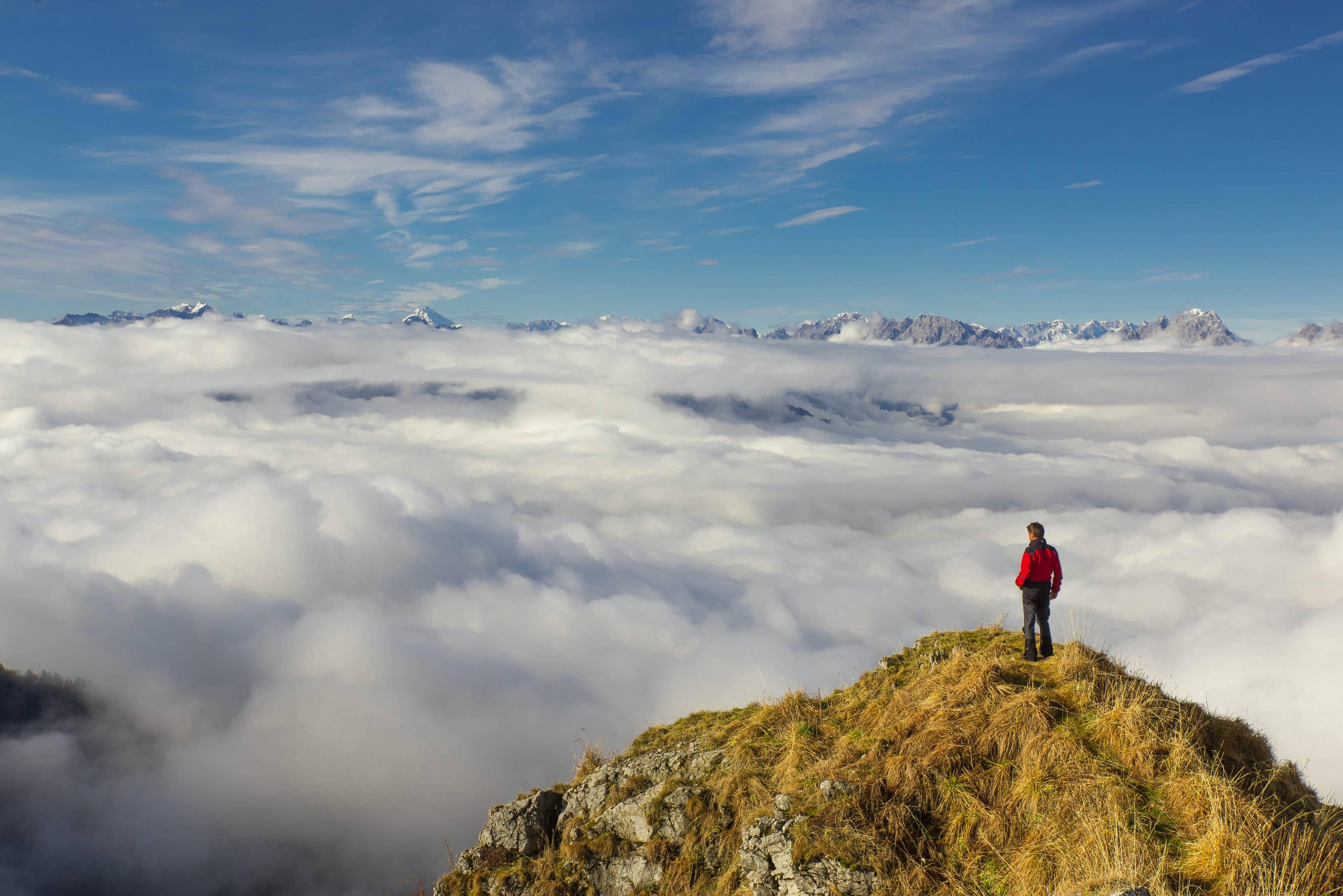 Man standing on mountain overlooking cloudy sky